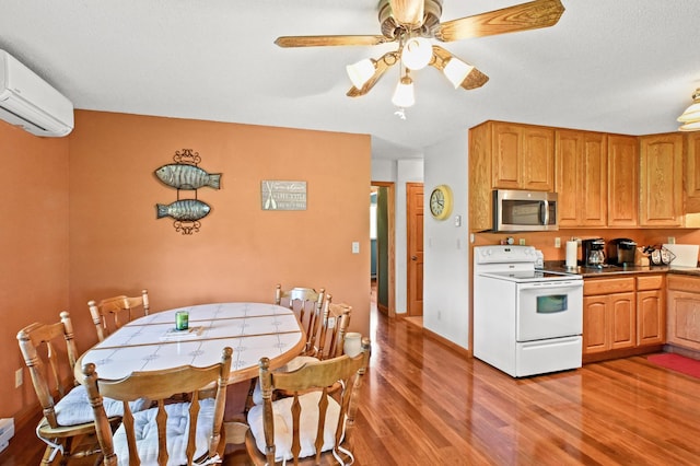 3865 Wahtomin Trl NW, Alexandria, MN 56308 - kitchen featuring white range with electric cooktop, stainless steel microwave, a wall mounted air conditioner, light wood-style floors, and a ceiling fan