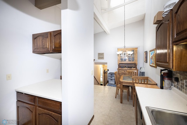 1427 23rd St S, Fargo, ND 58103 - kitchen with a chandelier, light countertops, high vaulted ceiling, pendant lighting, and dark brown cabinets