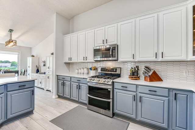 11001 Isanti Ct NE, Blaine, MN 55449 - kitchen featuring appliances with stainless steel finishes, vaulted ceiling, gray cabinetry, tasteful backsplash, and white cabinetry