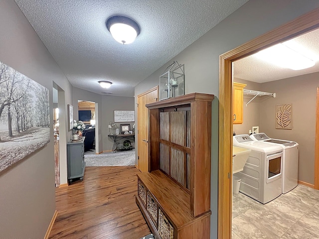 1209 23rd St SE, Willmar, MN 56201 - corridor featuring washer and clothes dryer, a textured ceiling, baseboards, and light wood-style floors