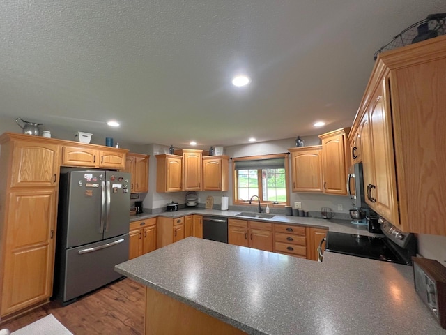 1209 23rd St SE, Willmar, MN 56201 - kitchen featuring appliances with stainless steel finishes, a sink, a peninsula, recessed lighting, and light wood-type flooring