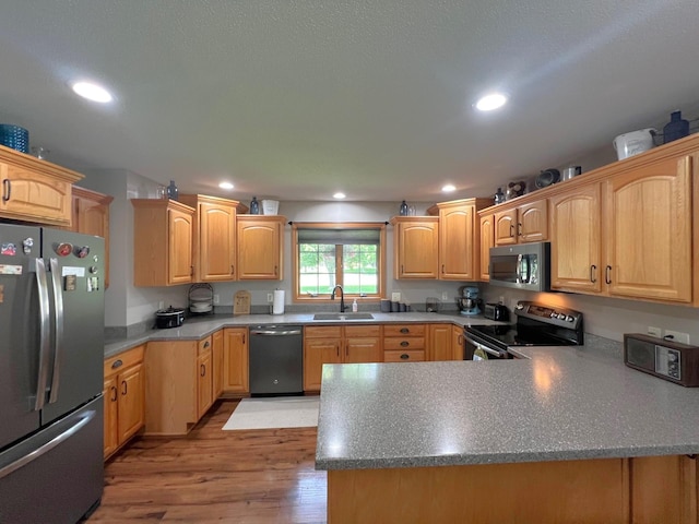 1209 23rd St SE, Willmar, MN 56201 - kitchen with appliances with stainless steel finishes, a sink, light wood-style floors, recessed lighting, and a peninsula