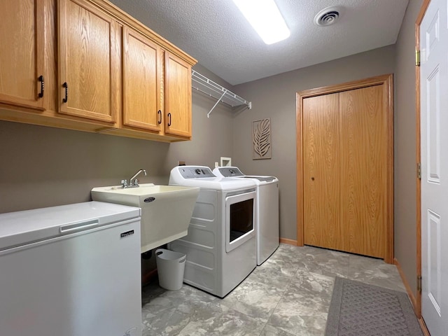 1209 23rd St SE, Willmar, MN 56201 - laundry area with washer and clothes dryer, cabinet space, and a textured ceiling