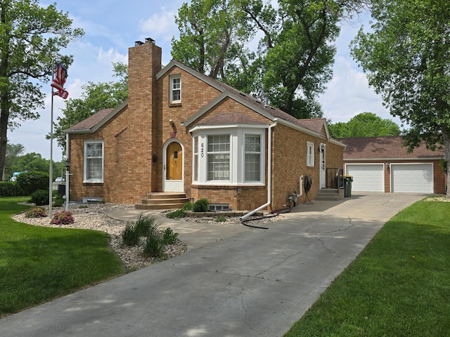 620 5th Ave SE, Pipestone, MN 56164 - tudor home featuring a chimney, brick siding, a front lawn, and a garage
