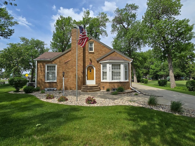 620 5th Ave SE, Pipestone, MN 56164 - tudor-style house featuring a front lawn, a chimney, and brick siding