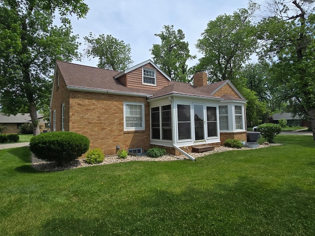 620 5th Ave SE, Pipestone, MN 56164 - back of house featuring a chimney, a sunroom, brick siding, and a yard