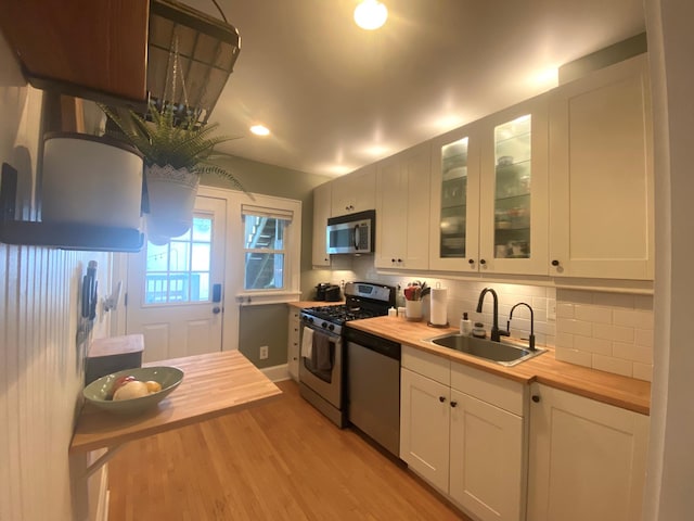 3112 Bryant Ave S Unit 1, Minneapolis, MN 55408 - kitchen featuring stainless steel appliances, wooden counters, a sink, light wood-type flooring, and white cabinets