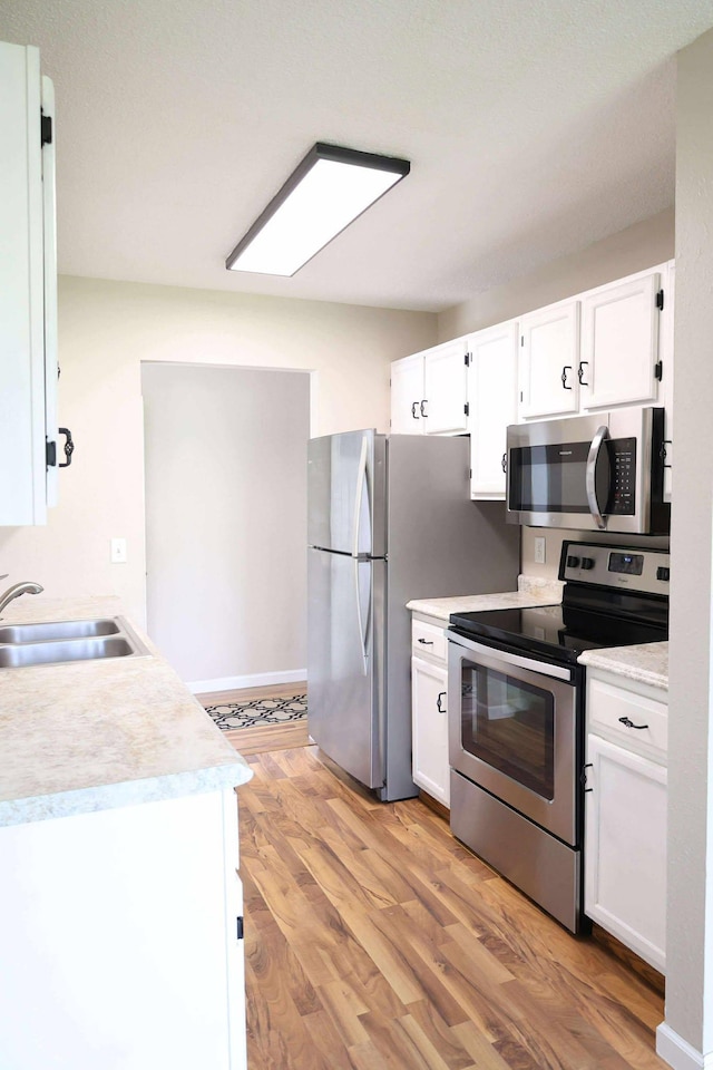 531 5th Street Ct E, West Fargo, ND 58078 - kitchen featuring appliances with stainless steel finishes, white cabinets, light wood-style flooring, and light countertops