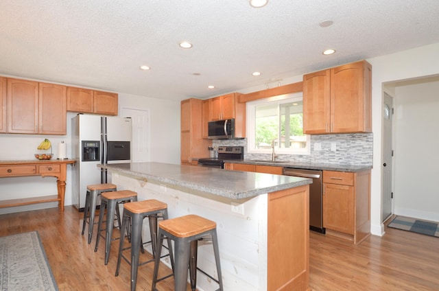 2603 140th Ln NW, Andover, MN 55304 - kitchen with stainless steel appliances, light wood finished floors, decorative backsplash, a kitchen island, and recessed lighting