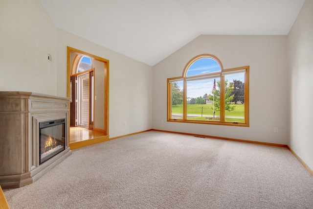 7811 209th St N, Forest Lake, MN 55025 - unfurnished living room with plenty of natural light, lofted ceiling, light carpet, and a glass covered fireplace