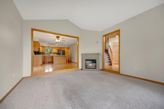 7811 209th St N, Forest Lake, MN 55025 - unfurnished living room with vaulted ceiling, light colored carpet, a glass covered fireplace, and a ceiling fan