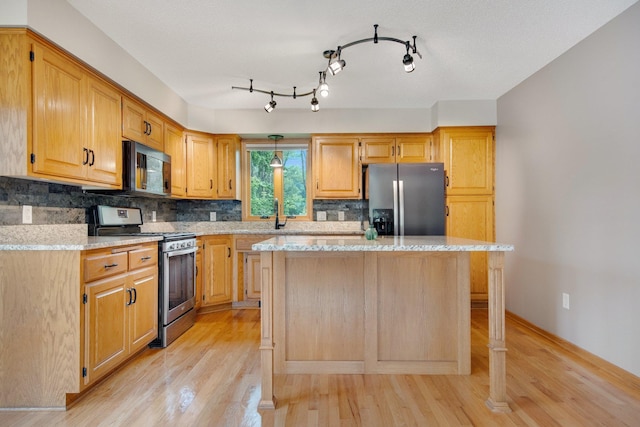 7811 209th St N, Forest Lake, MN 55025 - kitchen with stainless steel appliances, light wood-style floors, tasteful backsplash, a kitchen island, and light stone counters