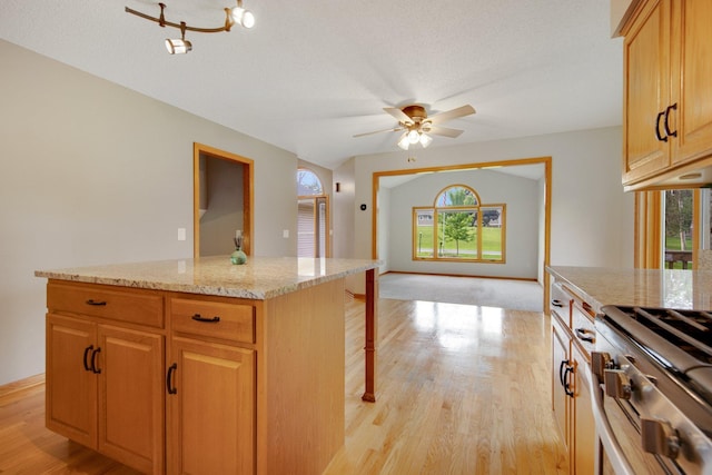 7811 209th St N, Forest Lake, MN 55025 - kitchen with plenty of natural light, a kitchen island, light wood finished floors, light stone countertops, and a textured ceiling