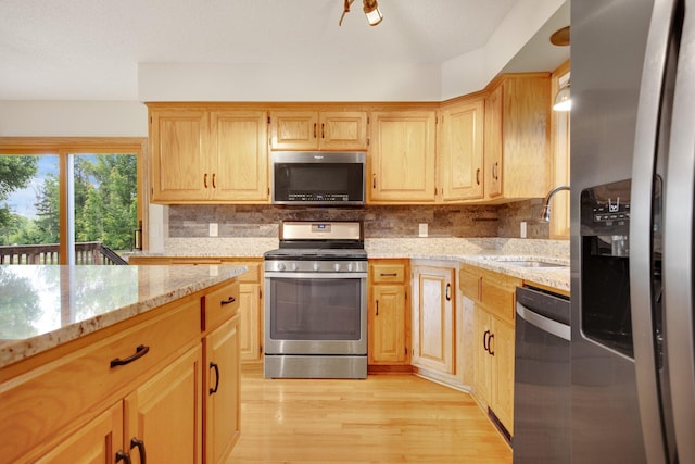 7811 209th St N, Forest Lake, MN 55025 - kitchen featuring appliances with stainless steel finishes, light stone counters, light wood finished floors, and tasteful backsplash