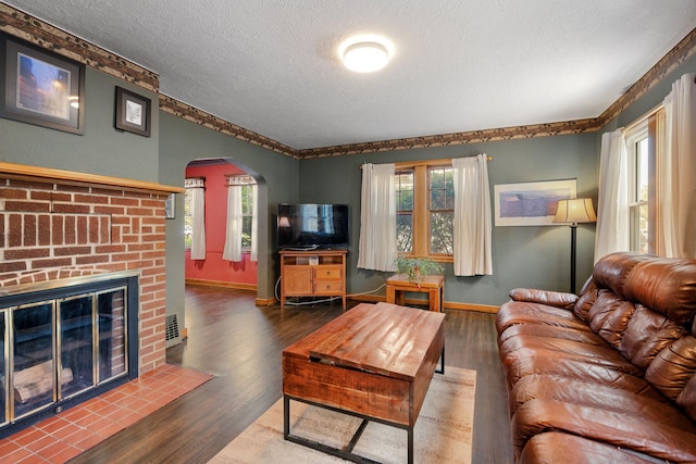 308 4th Ave SW, Austin, MN 55912 - living room featuring a textured ceiling, arched walkways, wood finished floors, baseboards, and a fireplace
