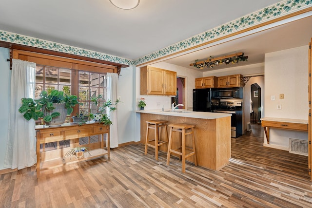308 4th Ave SW, Austin, MN 55912 - kitchen featuring black appliances, wood finished floors, light countertops, and a sink