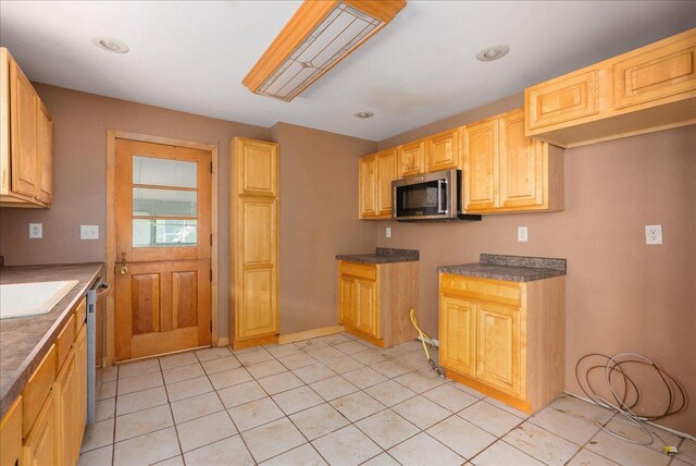 950 Clark St, Hammond, WI 54015 - kitchen with appliances with stainless steel finishes, light tile patterned floors, dark countertops, a sink, and baseboards