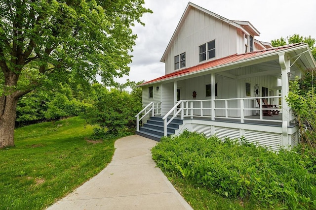 E2221 930th Ave, Stanton Twp, WI 54725 - view of front facade with board and batten siding, a porch, metal roof, and a front lawn