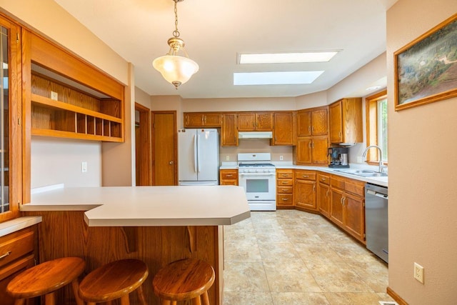 S363 Nicholes Rd, Naples Twp, WI 54755 - kitchen with white appliances, under cabinet range hood, a skylight, brown cabinets, and light countertops