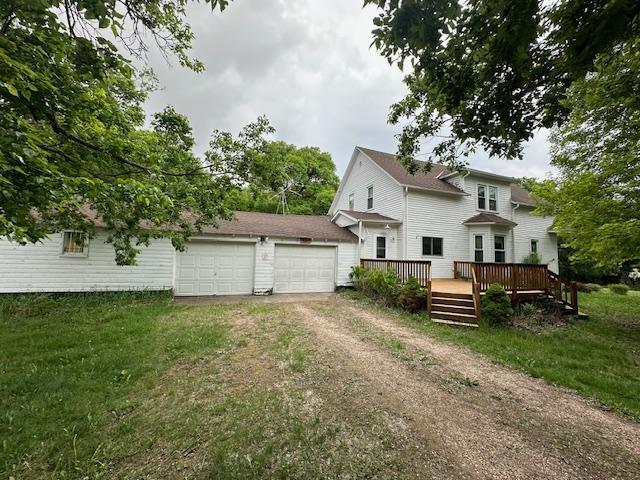 77729 330th St, Prior Twp, MN 56278 - back of property with driveway, an attached garage, a wooden deck, and a lawn