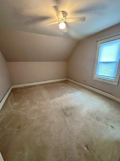 77729 330th St, Prior Twp, MN 56278 - additional living space featuring light carpet, vaulted ceiling, a ceiling fan, and baseboards