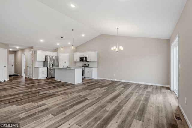 1009 2nd St NW, Delano, MN 55328 - unfurnished living room with a chandelier, lofted ceiling, wood finished floors, baseboards, and recessed lighting