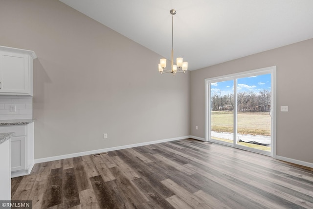 1009 2nd St NW, Delano, MN 55328 - unfurnished dining area featuring lofted ceiling, a chandelier, wood finished floors, and baseboards