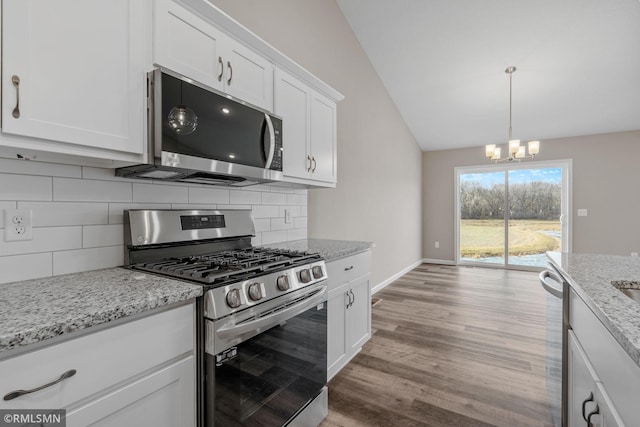 1009 2nd St NW, Delano, MN 55328 - kitchen with appliances with stainless steel finishes, vaulted ceiling, a chandelier, light wood finished floors, and white cabinetry