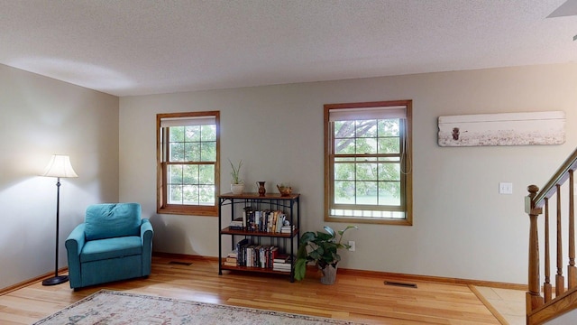 5121 Cameron Dr NW, Cascade Twp, MN 55901 - sitting room with wood finished floors, stairs, a textured ceiling, and baseboards