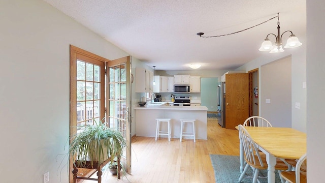 5121 Cameron Dr NW, Cascade Twp, MN 55901 - kitchen featuring appliances with stainless steel finishes, a peninsula, a sink, light wood-type flooring, and a chandelier