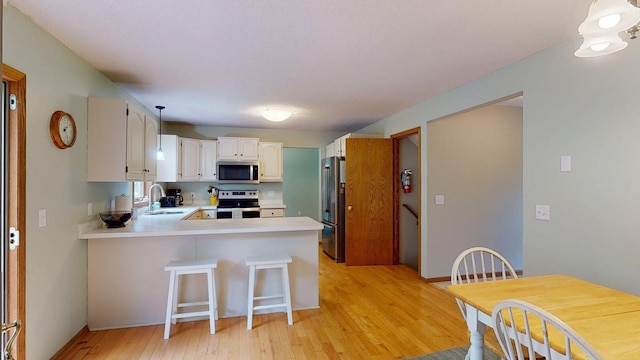5121 Cameron Dr NW, Cascade Twp, MN 55901 - kitchen with appliances with stainless steel finishes, a peninsula, light wood-type flooring, a sink, and light countertops