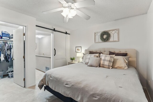 11219 16th St NE, Saint Michael, MN 55376 - bedroom featuring a barn door, a closet, a walk in closet, light colored carpet, and a textured ceiling