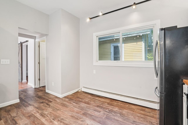 491 Belvidere St E, Saint Paul, MN 55107 - spare room featuring a baseboard heating unit, wood finished floors, a barn door, and baseboards