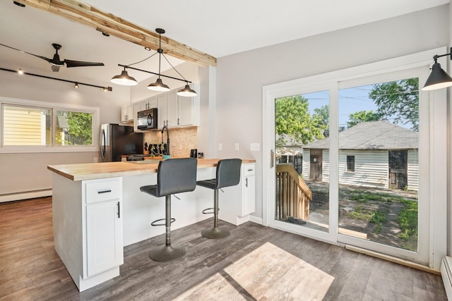 491 Belvidere St E, Saint Paul, MN 55107 - kitchen with black microwave, butcher block countertops, dark wood-type flooring, decorative backsplash, and white cabinets