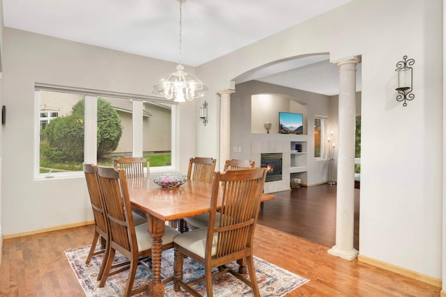 6242 Cavendish Pl, Eden Prairie, MN 55346 - dining space featuring arched walkways, light wood-type flooring, decorative columns, a fireplace, and a chandelier