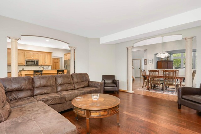 6242 Cavendish Pl, Eden Prairie, MN 55346 - living area featuring ornate columns, dark wood-style floors, a chandelier, recessed lighting, and arched walkways