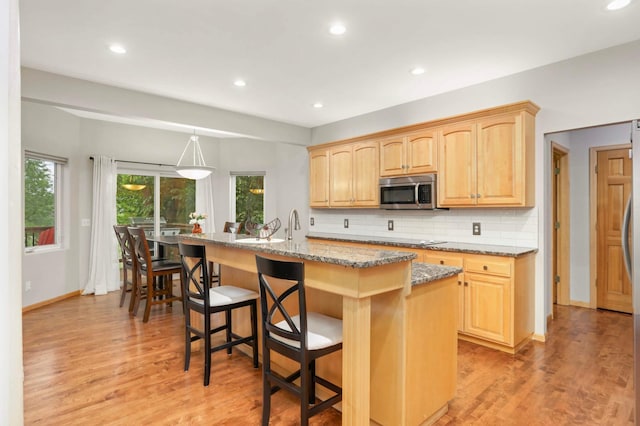 6242 Cavendish Pl, Eden Prairie, MN 55346 - kitchen featuring stainless steel microwave, light brown cabinetry, light wood-style flooring, light stone counters, and recessed lighting