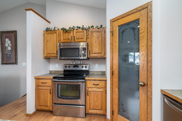 1022 Wilson Ave, Crookston, MN 56716 - kitchen with stainless steel appliances, light wood finished floors, lofted ceiling, and brown cabinetry