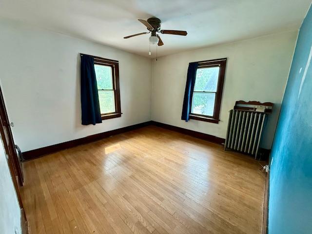 105 Oak St N, Mabel, MN 55954 - spare room with radiator heating unit, plenty of natural light, wood finished floors, and ceiling fan