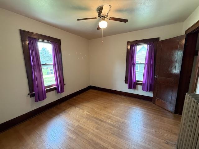 105 Oak St N, Mabel, MN 55954 - spare room with radiator heating unit, wood finished floors, baseboards, and ceiling fan