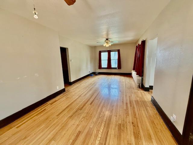 105 Oak St N, Mabel, MN 55954 - spare room featuring ceiling fan, radiator heating unit, light wood finished floors, and baseboards