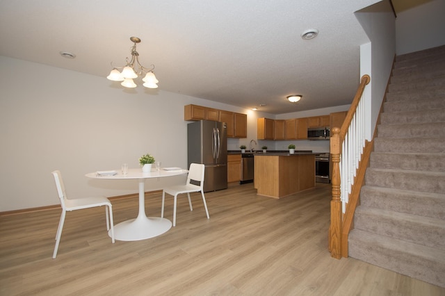 412 Cedar Pl, Maple Lake, MN 55358 - kitchen featuring stainless steel appliances, a chandelier, light wood-style flooring, dark countertops, and a kitchen island