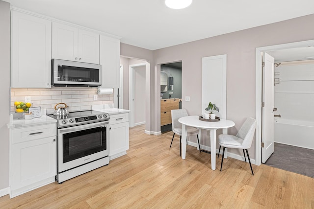 232 26th Ave N, Saint Cloud, MN 56303 - kitchen with appliances with stainless steel finishes, light wood finished floors, light countertops, backsplash, and white cabinets