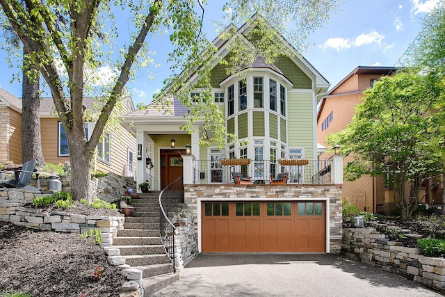 1241 Cedar Lake Rd S, Minneapolis, MN 55416 - victorian house with an attached garage, asphalt driveway, stone siding, and stairs