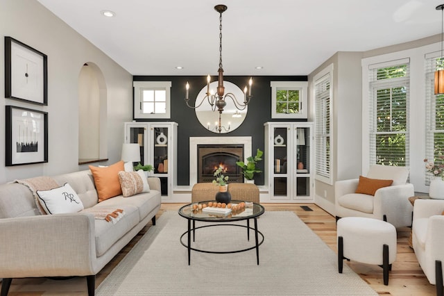 1241 Cedar Lake Rd S, Minneapolis, MN 55416 - living area featuring wood finished floors, a chandelier, arched walkways, a warm lit fireplace, and recessed lighting
