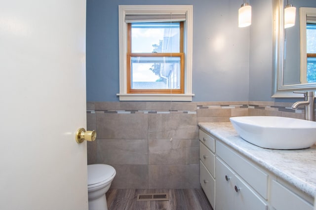 1618 10th St N, Fargo, ND 58102 - half bathroom featuring tile walls, vanity, toilet, and wainscoting