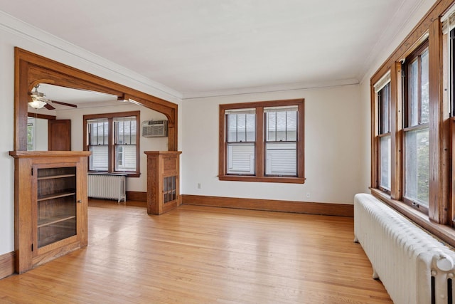 1601 Charles Ave, Saint Paul, MN 55104 - unfurnished living room featuring radiator, light wood finished floors, ornamental molding, an AC wall unit, and a ceiling fan