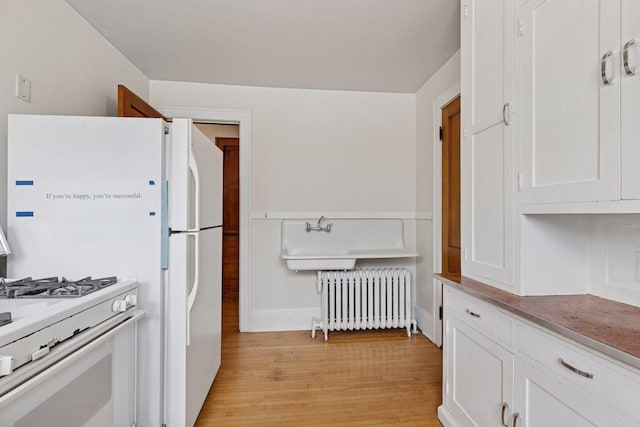 1601 Charles Ave, Saint Paul, MN 55104 - kitchen featuring radiator, white gas range oven, light wood-type flooring, and white cabinets