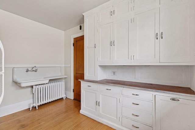 1601 Charles Ave, Saint Paul, MN 55104 - kitchen with radiator, light wood-type flooring, and white cabinets
