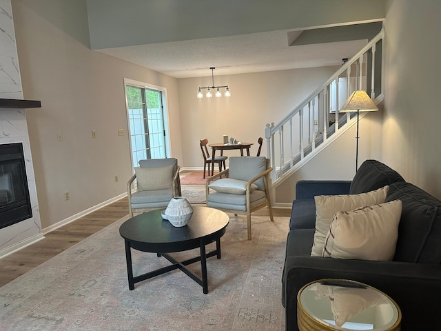691 85th Ln NW Unit 1, Coon Rapids, MN 55433 - living room featuring wood finished floors, stairs, a chandelier, baseboards, and a premium fireplace